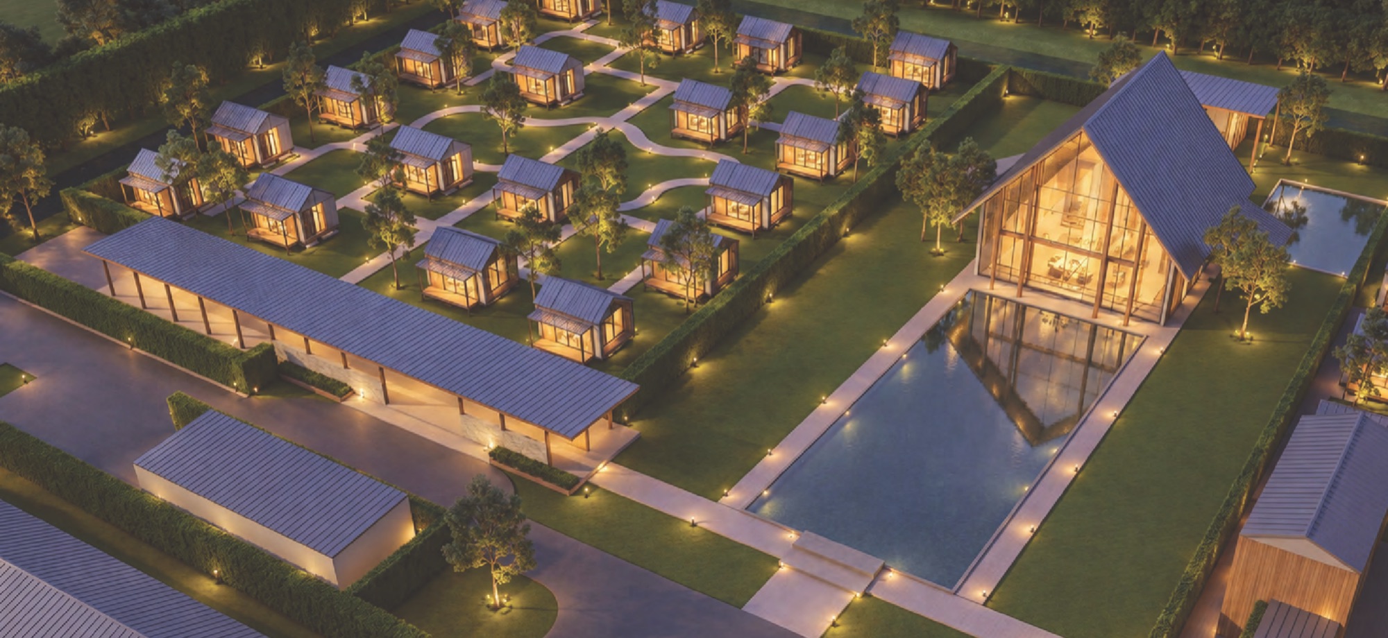 Concept design of Vimutti Valley at night: the meditation hall lit from within beside a reflecting pool, small houses among the gardens